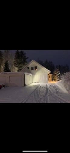a white house with a garage in the snow at Charming room with big bed in Luleå
