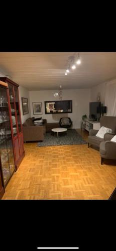 a living room with a wooden floor and a living room with couches at Charming room with big bed in Luleå