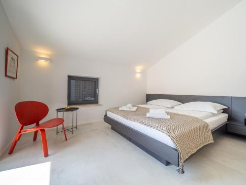 ein Schlafzimmer mit einem Bett und einem roten Stuhl in der Unterkunft Villa Greta in Risika