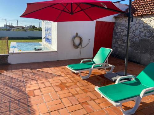 a patio with chairs and an umbrella and a pool at Moita Cottage in Moita