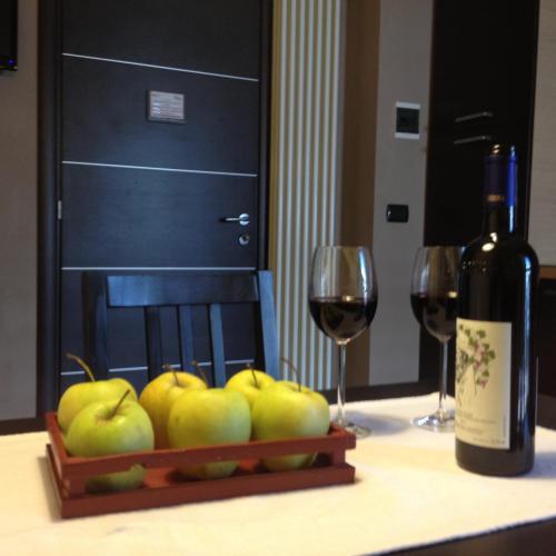 a bottle of wine and a bowl of apples on a table with two glasses at Casa Bona in Alba