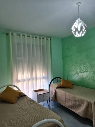 two beds in a room with a green wall at Apartment Aulona Park in Vlorë