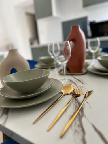 a table with plates and forks and glasses on it at Le Saphir de Calais - Chic et élegant in Calais