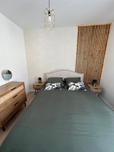 a bedroom with a large bed and a wooden dresser at Le Saphir de Calais - Chic et élegant in Calais