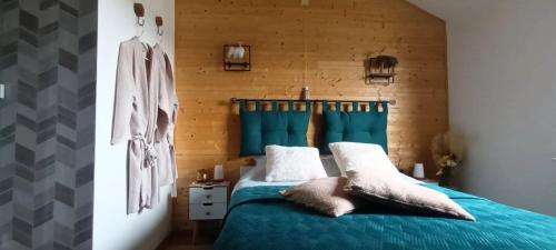 een slaapkamer met een blauw bed en een houten muur bij Chez Seb & Lulu, studio d'hôtes in Neufchâteau