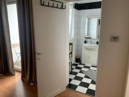 uma casa de banho com piso em xadrez preto e branco em Coco’s place em Antuérpia