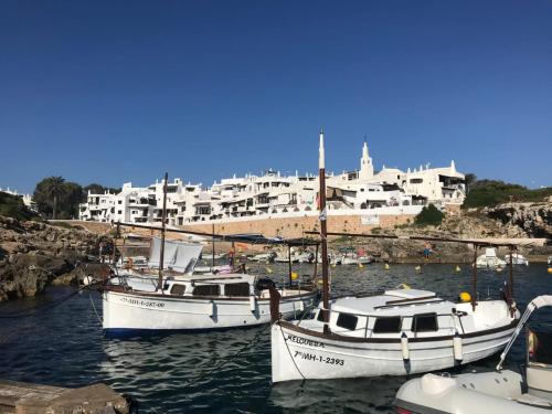 três barcos ancorados num porto com edifícios ao fundo em Coves Noves Nice apartment of 75 m2 10 minutes walk from the beach of Arenal d'en Castell em Es Mercadal