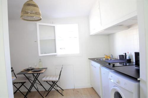 eine weiße Küche mit einem Waschbecken und einem Tisch in der Unterkunft Le Nid - Au cœur du Cours Julien in Marseille