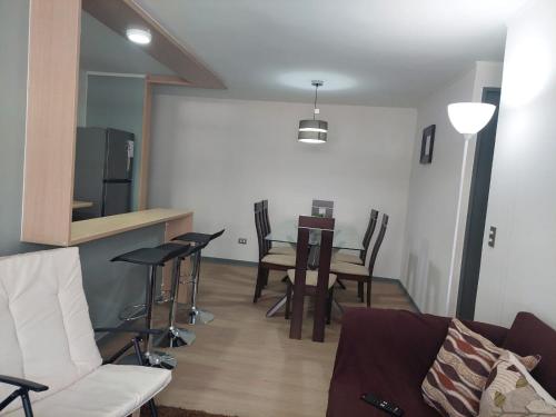 a living room with a couch and a table with chairs at Hermoso departamento nuevo amoblado in Arica