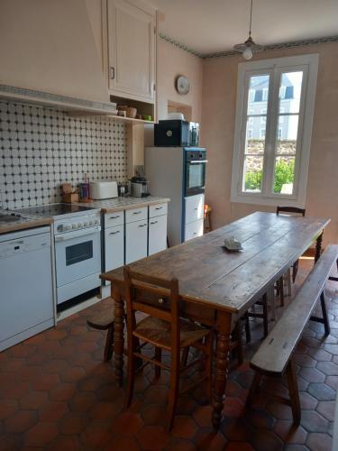 eine Küche mit einem Holztisch und einem Tisch und Stühlen in der Unterkunft Chambres à louer centre-ville in Le Mans