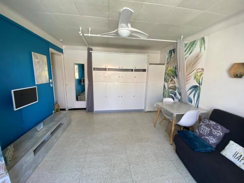 een woonkamer met een bank en een plafondventilator bij Grand studio cosy à 300m de la mer avec parking in Canet-en-Roussillon