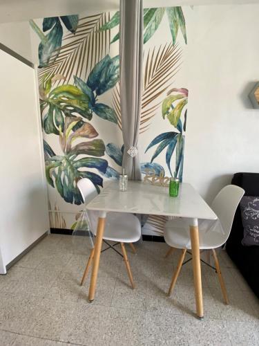 een tafel en twee stoelen in een kamer met een muurschildering bij Grand studio cosy à 300m de la mer avec parking in Canet-en-Roussillon