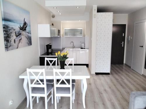 a kitchen and dining room with a white table and chairs at Apartament Kasztanowy in Władysławowo