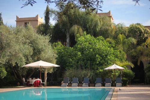 a swimming pool with chairs and umbrellas at La Maison Arabe Hotel, Spa & Cooking Workshops in Marrakech