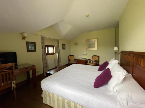 - une chambre avec un grand lit blanc et des oreillers violets dans l'établissement Quinta de Villanueva, à Colombres