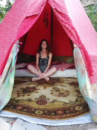 a woman sitting on a bed in a tent at @gatetothewild in Coreglia Ligure