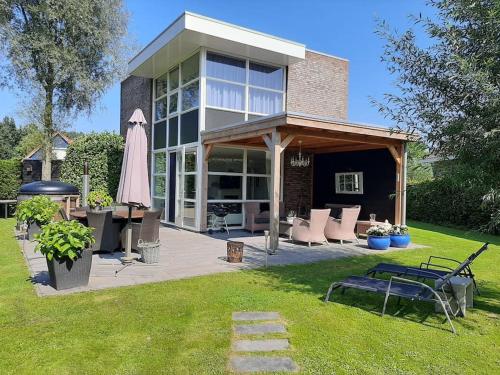 a house with a patio and an umbrella in the yard at Gastehuisie Lekkerslaap in Zeewolde
