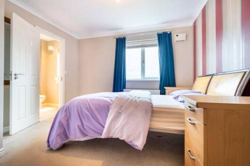 a bedroom with a large bed with blue curtains at Bulkington Lodge Coventry - Affordable Cosy Double & En-Suite Rooms in Bulkington