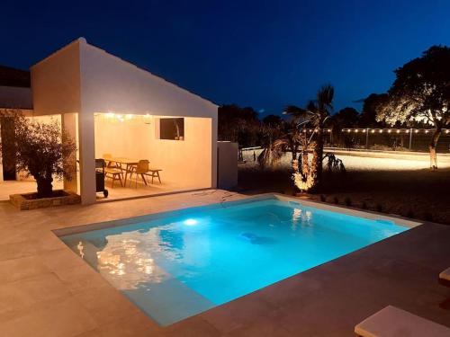 - une piscine en face d'une maison la nuit dans l'établissement Villa moderne entre centre ville et nature, à Nîmes