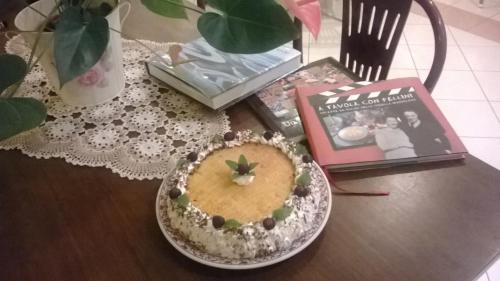 a table with a cake and a magazine and a book at Hotel Rosati in Rimini