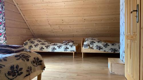 two beds in a room with wooden walls at Domki na wzgórzu 2 in Małe Ciche