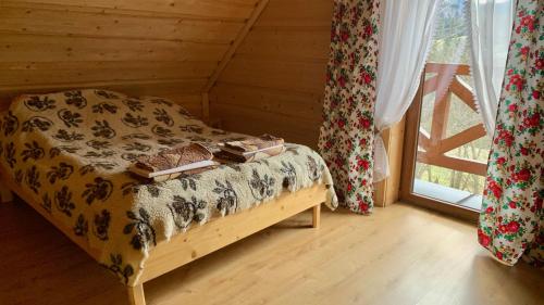 een slaapkamer met een bed met boeken en een raam bij Domki na wzgórzu 2 in Ciche Małe
