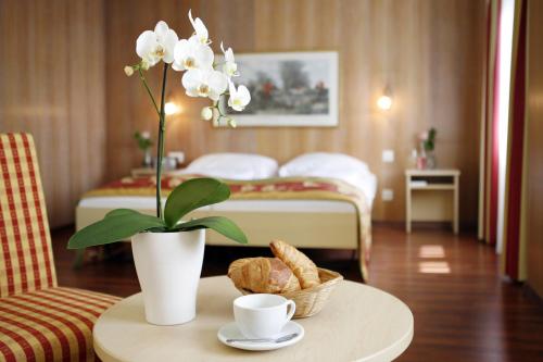 ein Hotelzimmer mit einem Tisch mit Blumen und einem Bett in der Unterkunft Hotel De la Paix in Luzern