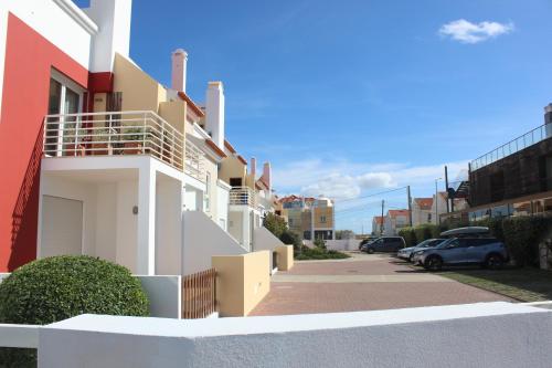 a white building with a parking lot with cars parked at Carlota House - Baleal in Baleal