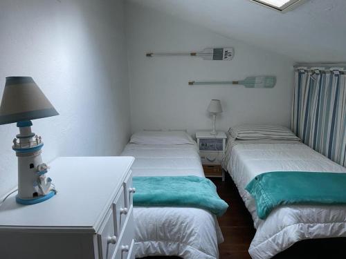 a bedroom with two beds and a table with a lamp at Santa Margherita di Pula, Calaverde, Deliziosa villetta 100 metri dal mare in Santa Margherita di Pula