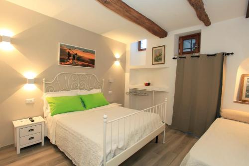 um quarto com uma cama branca e almofadas verdes em La casa di Ines em San Gimignano