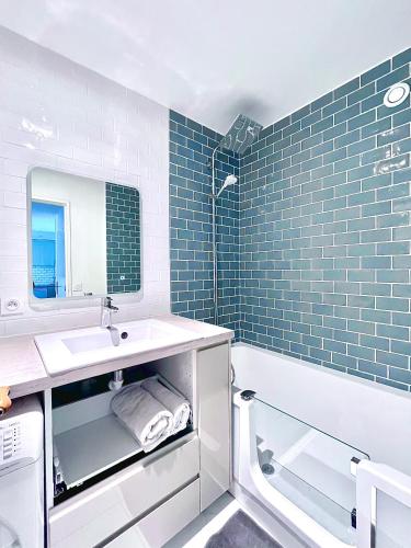 ein Badezimmer mit blauen Fliesen, einem Waschbecken und einer Badewanne in der Unterkunft Bel appartement complet: in Villetaneuse