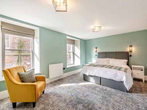 ein Schlafzimmer mit grünen Wänden, einem Bett und einem Stuhl in der Unterkunft The Embassy in Eyemouth