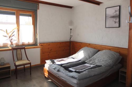 Bett in einem Zimmer mit einem Stuhl und einem Fenster in der Unterkunft Muskátli Vendégház in Szeged