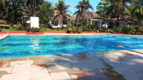 a large swimming pool with palm trees and a house at LUISA BY THE SEA VILLAS in Cavelossim