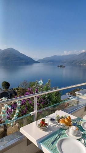 uma mesa com pratos de comida numa varanda com vista para um lago em Sollevante Ascona em Ascona