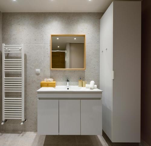 een badkamer met een witte wastafel en een spiegel bij Blu & Marrone Suites-free parking in Thessaloniki