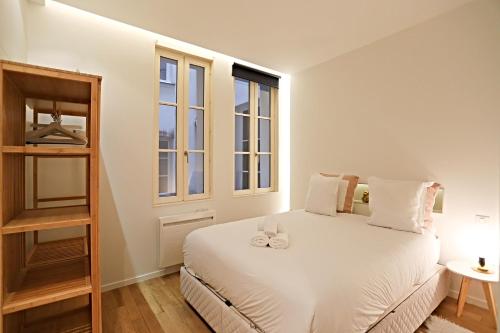 sypialnia z łóżkiem z białą pościelą i oknami w obiekcie APPARTEMENT PARIS - LOUVRE & RIVOLI w Paryżu
