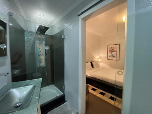 a bathroom with a sink and a shower and a bed at Villa Madeira island in Caniço