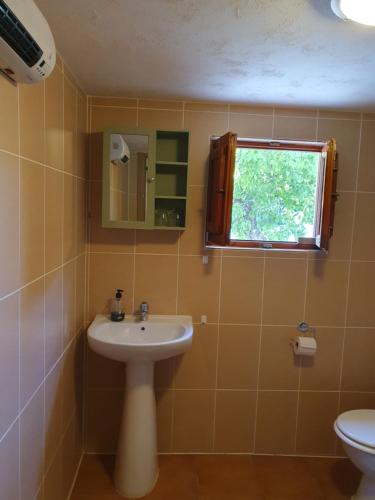 baño con lavabo y aseo y ventana en Casita of Casa Olivar, en Tocon