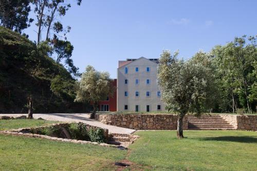 a building in the middle of a park with a tree at HD | Duecitânia Design Hotel in Penela