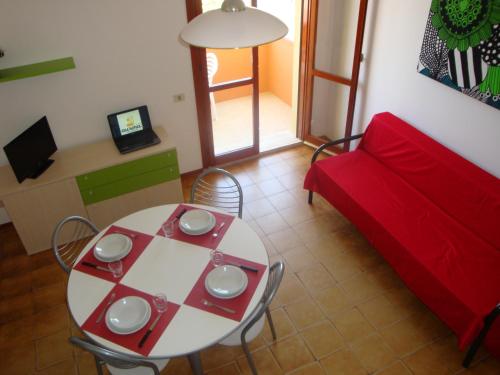 ein Wohnzimmer mit einem Tisch und einem roten Sofa in der Unterkunft Aurora Residence in Lido Adriano