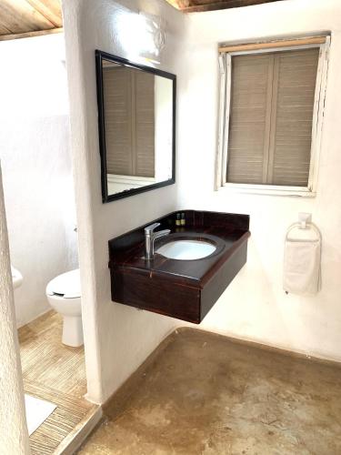 a bathroom with a sink and a mirror and a toilet at Villa Polinesia Chamela in Pérula