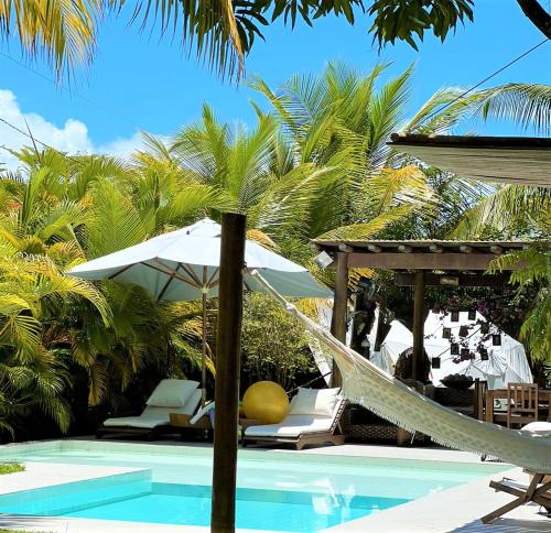 una hamaca y sillas junto a una piscina con palmeras en Pé na Areia - Pousada, en Barra Grande