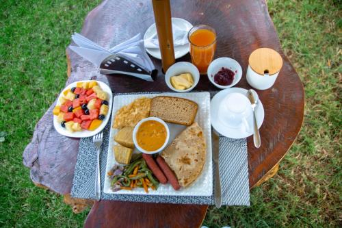 a picnic table with a plate of food and drinks at Shose Farm House & Chalets in Moshi