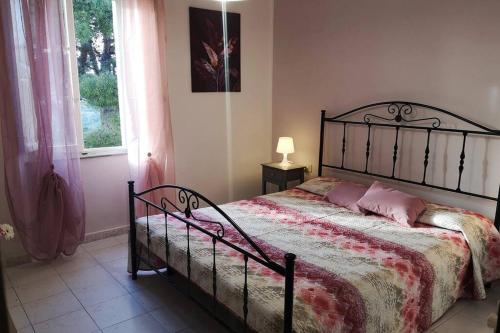 a bedroom with a bed with pink pillows and a window at La casa dei nonni in Capoliveri