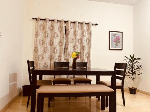 comedor con mesa, sillas y cortina en Nilgiri Comfort Stay, en Coonoor