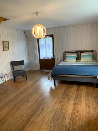 um quarto com uma cama e uma cadeira em La ferme d'aristide em Saillenard
