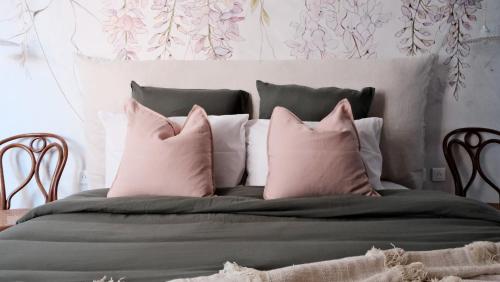 ein Bett mit rosa und grauen Kissen darauf in der Unterkunft Un air de campagne à Baudival in Le Cateau