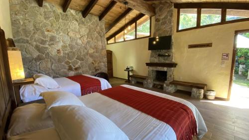 een slaapkamer met 2 bedden en een stenen muur bij Cabañas La Cascada in Zacatlán