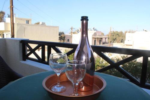 a bottle of wine and two glasses on a table at Rodi Apartments 1 in Kamari